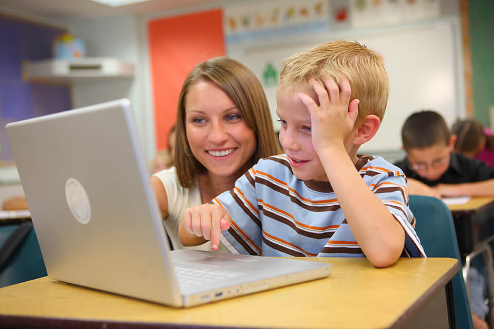 SPED teacher helping student with teletherapy session in class