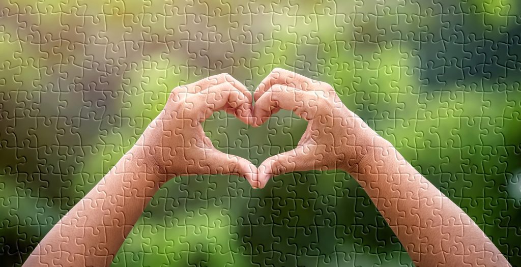 Puzzle of hands forming heart and held up high