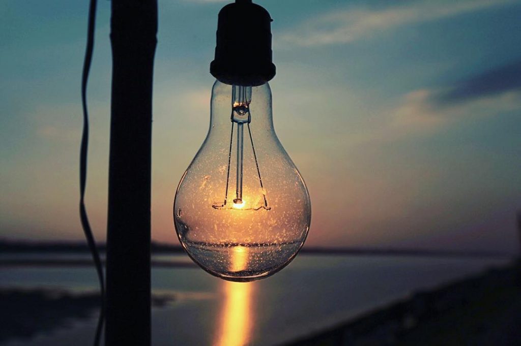 Lightbulb illuminated with sunset near the ocean