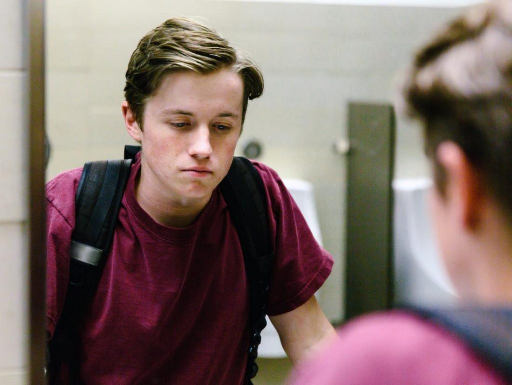 Depressed student looking in mirror, suicide awareness