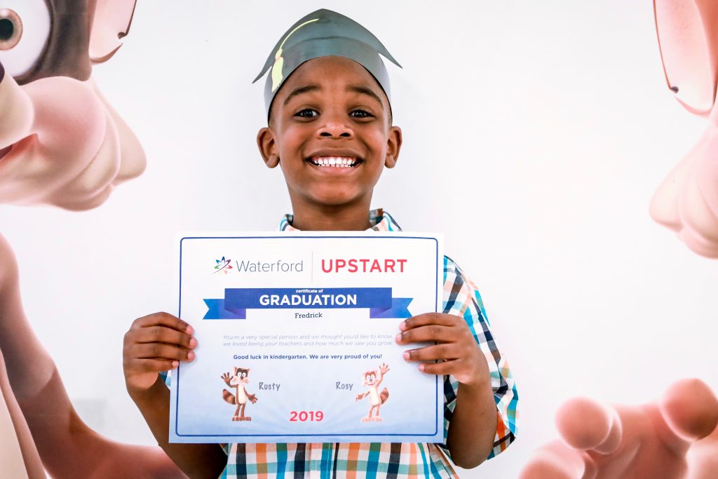 Child holding Wateford Upstart graduation certificate